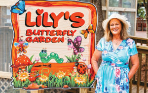 woman in flowery dress smiling with lilys butterfly garden sign at boggy creek airboat adventures
