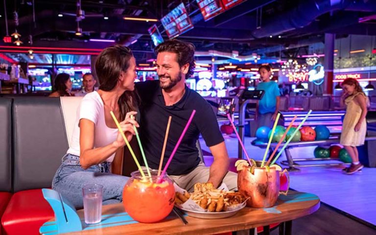 couple bowling with colorful cocktails and neon lighting at dania pointe fort lauderdale