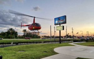 red helicopter landing on pad with sign near road at orlando helicopter adventures kissimmee