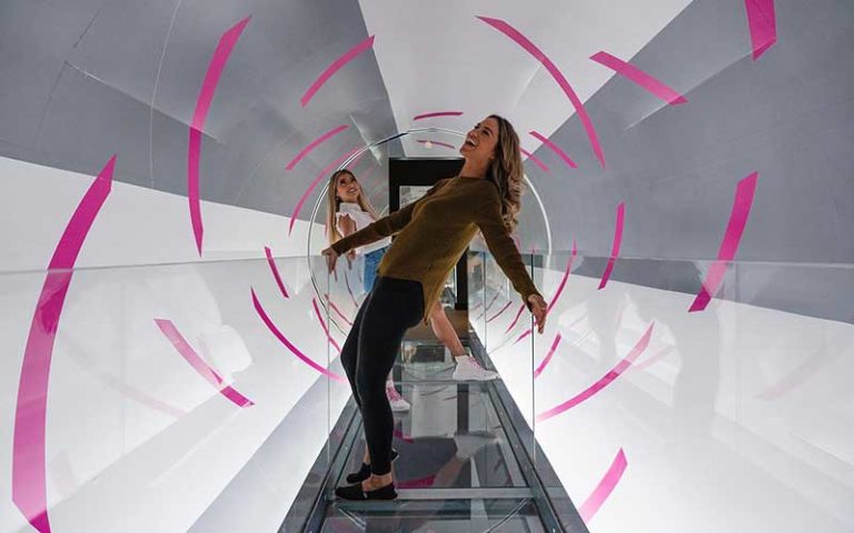 two women leaning opposite ways in tunnel at paradox museum miami