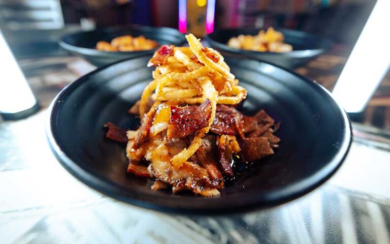 black bowl with mashed potatoes bacon and onion straws on lighted bar at sickies garage burgers and brews kissimmee