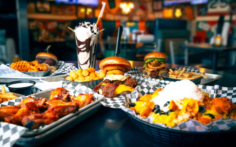 dining table loaded with entrees nachos milkshake burgers at sickies garage burgers and brews