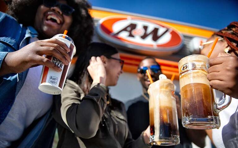 group of young people laughing with root beer drinks and restaurant sign at a&w all american food old town