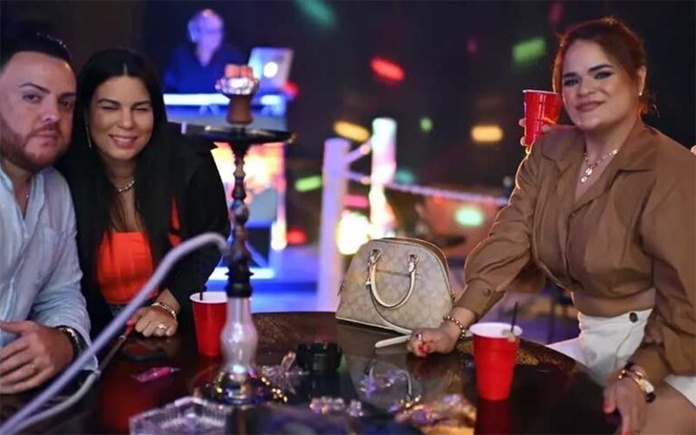 man and two women smiling sitting at hookah table with nightclub background at perfectos lounge orlando