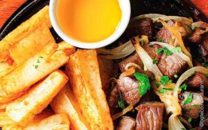 sauted steak onions and peppers with fries and yellow sauce on a black plate at boteco restaurant orlando