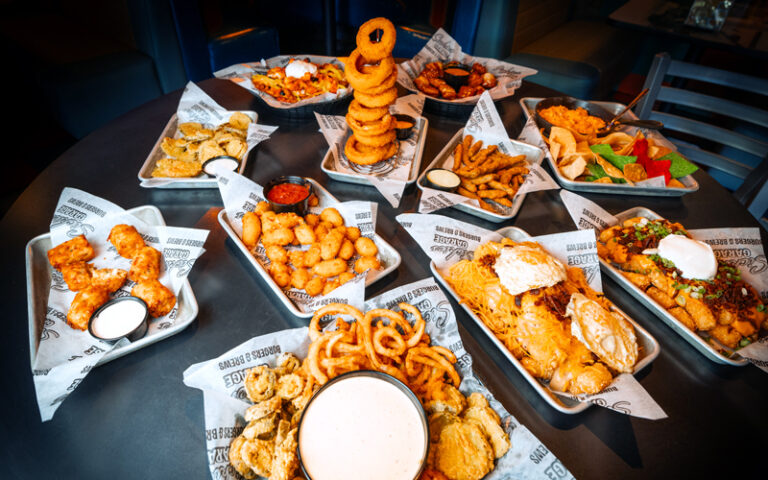several entrees with stacked onion rings at sickies garage burgers and brews