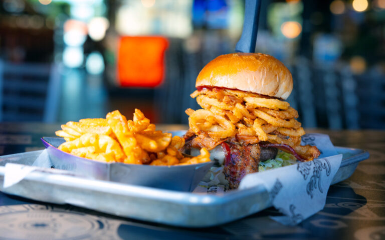 tall stacked burger with fries and bacon at sickies garage burgers and brews