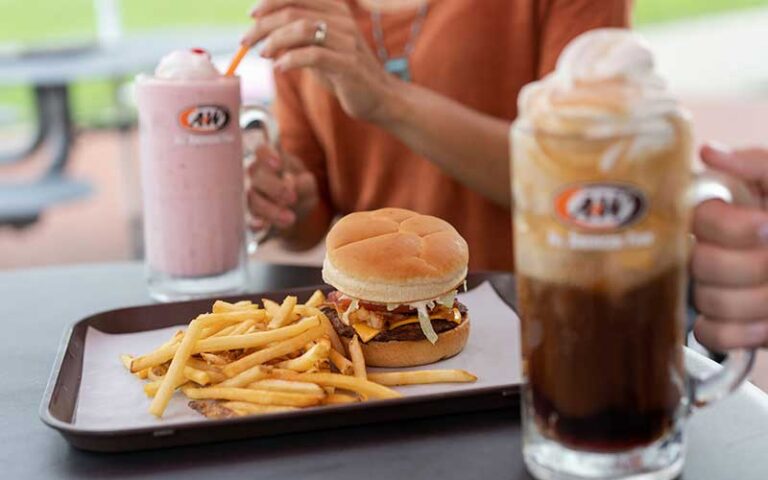 two people at a table with root beer float and strawberry milkshake and burger and fries on tray at a&w all american food old town