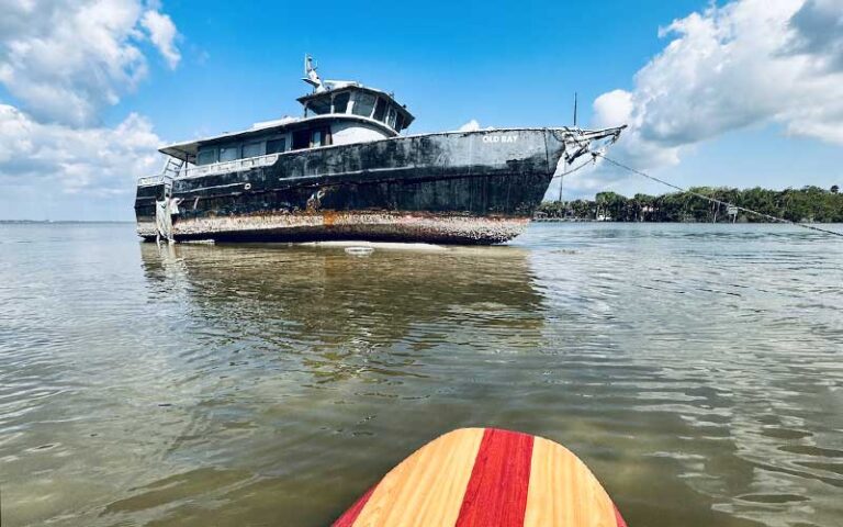 view over water with red striped board nose and shipwreck with inlet bank in background at three brothers adventure tours cocoa beach