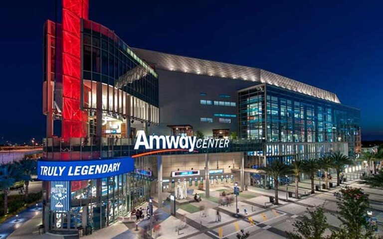 aerial of front exterior of arena at night with lighting red and blue at amway center orlando