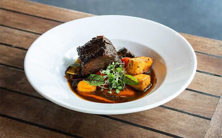 beef entree in white plate on wood at orsay jacksonville