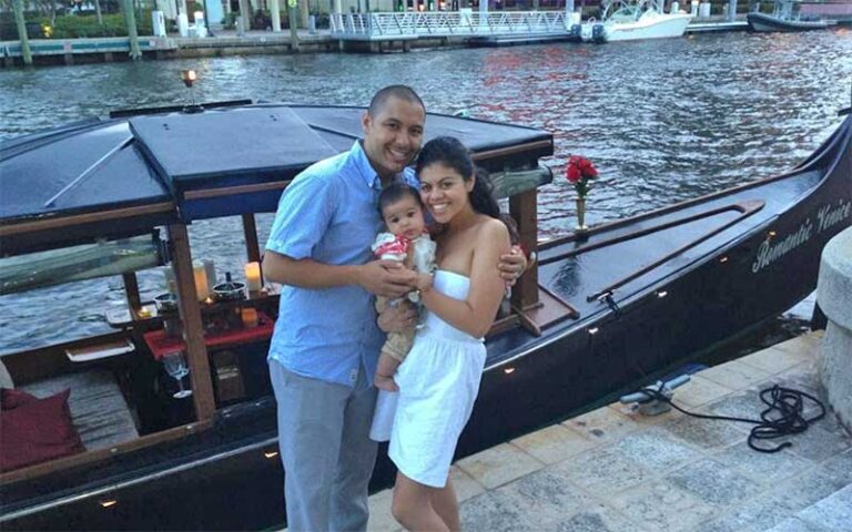 couple with baby on dock with boat behind at las olas gondola fort lauderdale