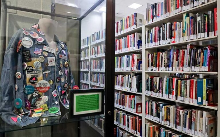 denim jacket with buttons exhibit in case next to book shelves at stonewall national museum archives ft lauderdale