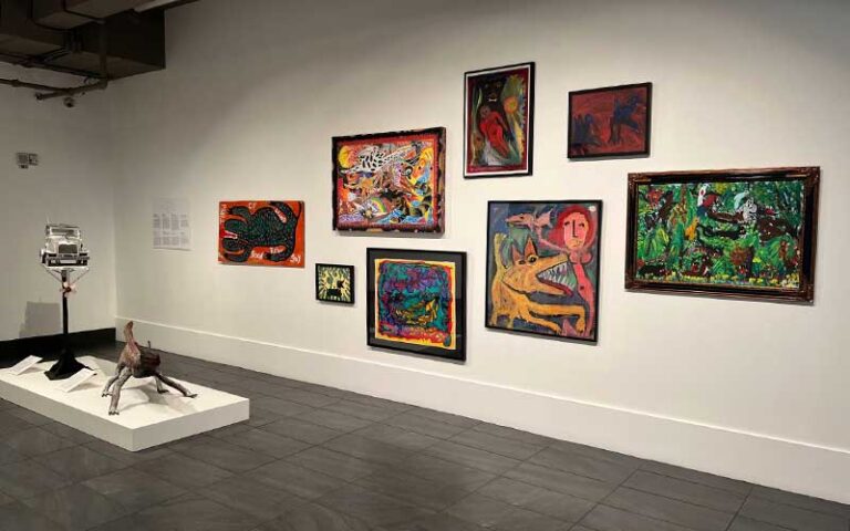 exhibit wall with array of paintings and sculpture on platform at mennello museum orlando