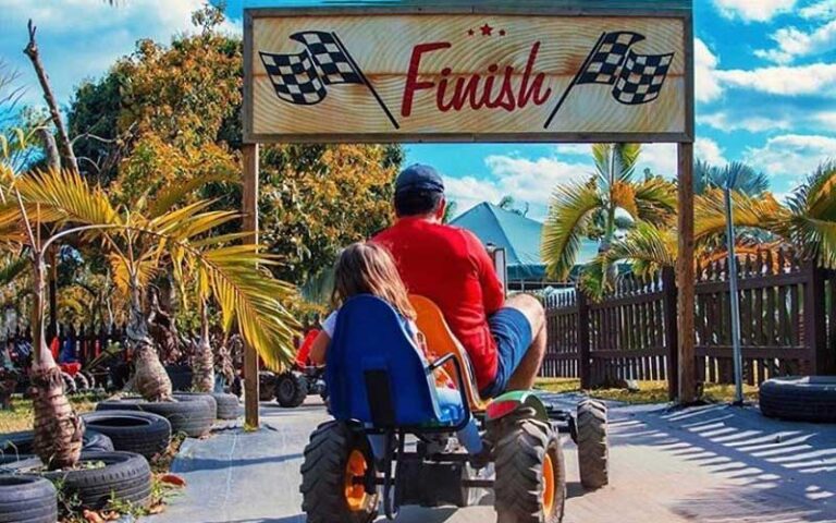 father and daughter on tractor pedal car driving through finish line at pintos farm miami