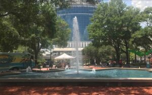 fountain with multiple heads and glass building behind with flanking trees at james weldon johnson park jacksonville