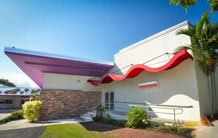 front exterior angled with red wave pattern awning and purple eave with sign at stonewall national museum archives ft lauderdale post