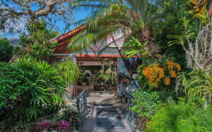 front exterior of greenhouse with walkway sign and lush tropical trees at r f orchid homestead
