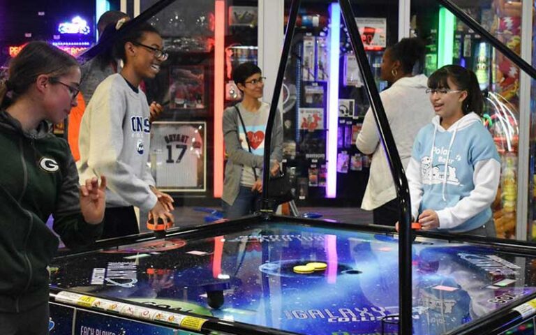 group of kids in an arcade playing air hockey and cheering at autobahn indoor speedway events jacksonville
