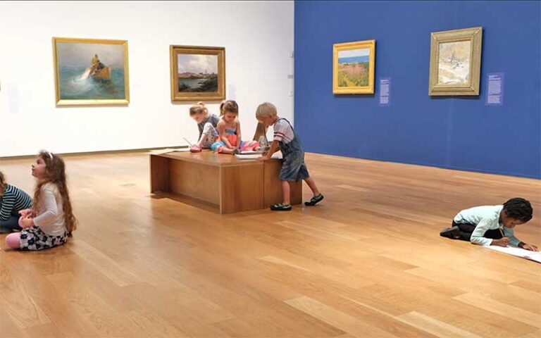 kids drawing on pads while looking at oil paintings in exhibit room at orlando museum of art