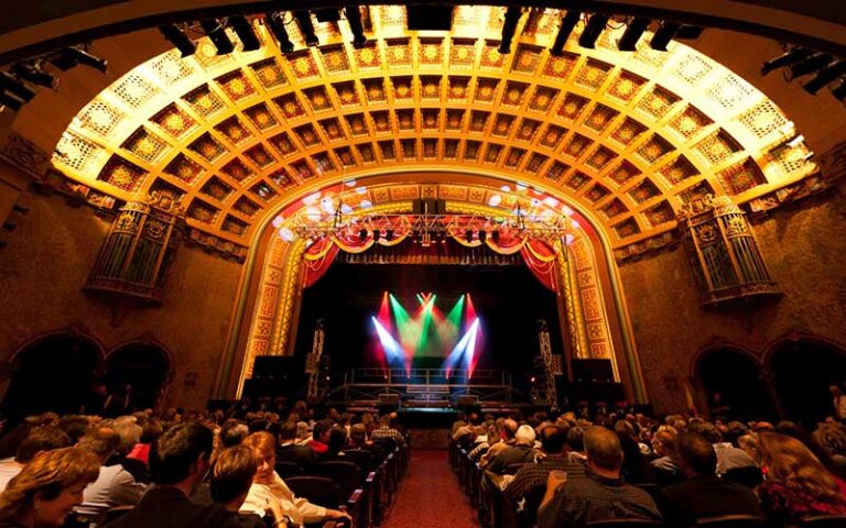 large theater with colorful spot lights on stage and crowded seating at florida theatre jacksonville