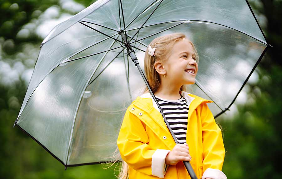 little girl with transparent umbrella standing in park
