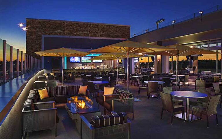 outdoor at night rooftop lounge area with patio umbrellas and viewing deck at topgolf jacksonville