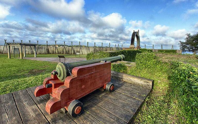 outdoor field with cannon on red cart mount at fort caroline national memorial jacksonville