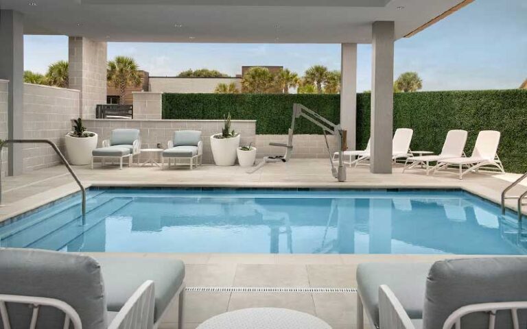 outdoor pool with chairs hedges and planters at element jacksonville beach