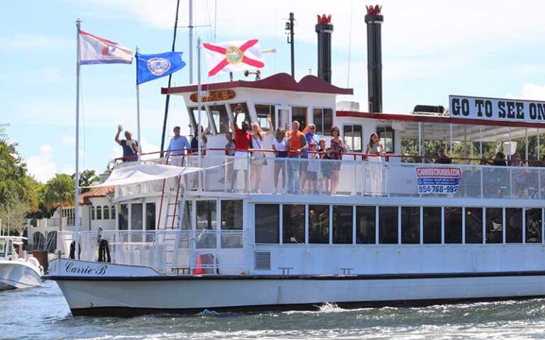 people waving from upper deck of tour boat with flags at carrie b cruises ft lauderdale