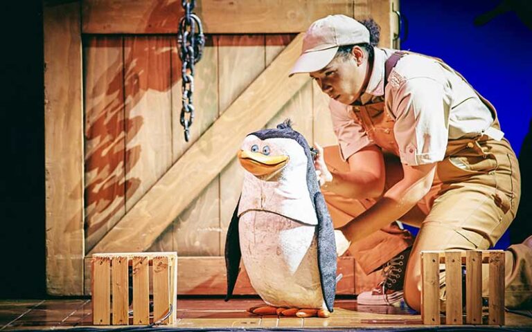 puppeteer performing with penguin puppet on stage at florida theatre jacksonville