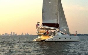 sailboat moving across water with city skyline at now and zen sailboat charters jacksonville