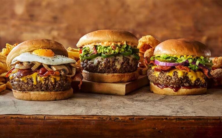 three specialty burgers with fries on sideboard at teds montana grill jacksonville