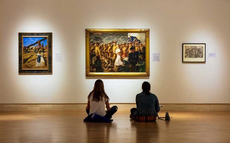 two young girls sit on floor of museum looking at painting in exhibit at cummer museum of art and gardens jacksonville