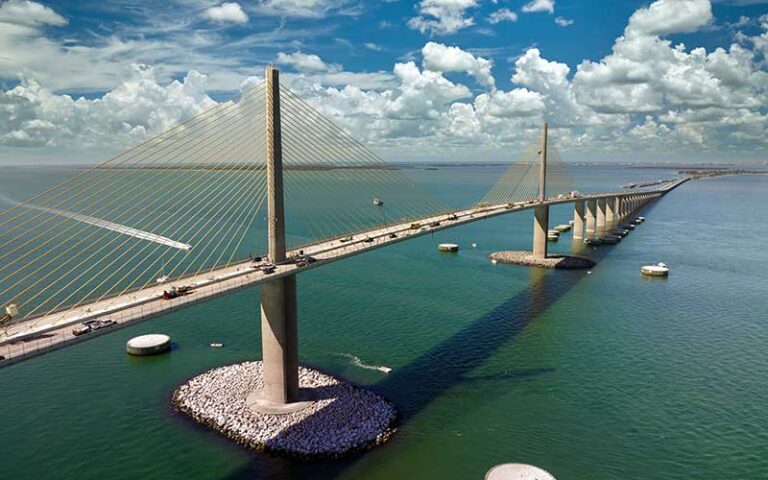 view across water of two pillar suspension bridge and cloudy sky at sunshine skyway bridge tampa st pete
