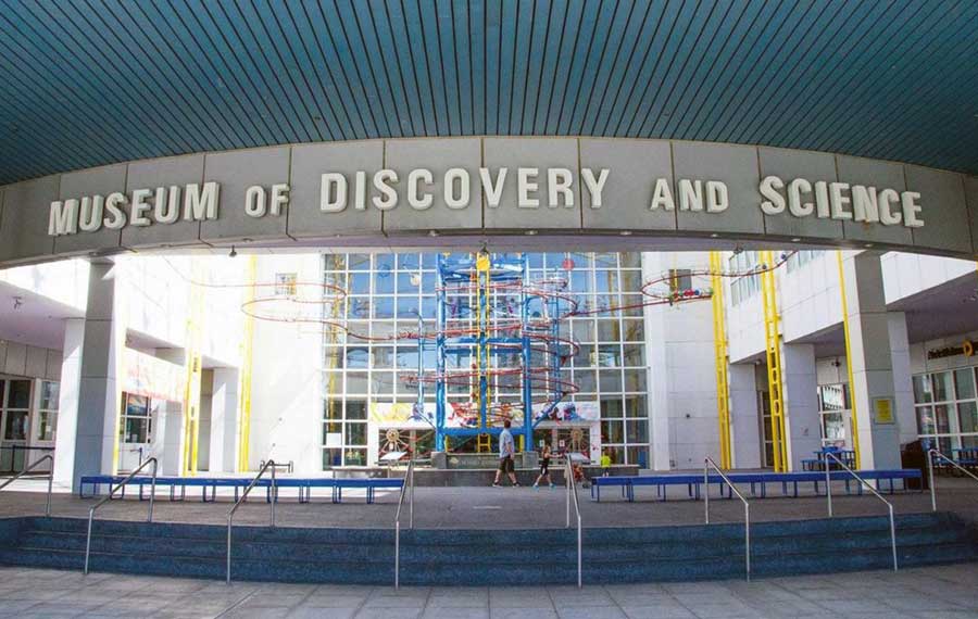 view of steps with lettered sign in an atrium with colorful pipes and exhibit windows at museum of discovery and science ft lauderdale post