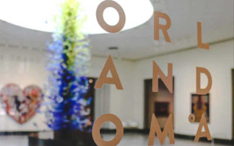 view through glass door with name and glass sculpture in lobby at orlando museum of art