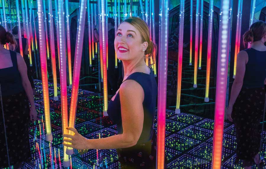 woman smiling holding led light tube in mirror maze attraction at ripleys