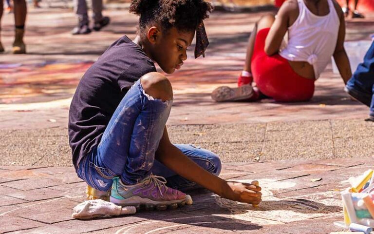 young girl drawing art with chalk on pavers at james weldon johnson park jacksonville