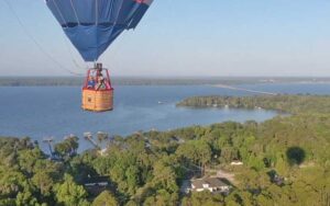 aerial of neighboring balloon above landscape with lake and trees at a hot air balloon ride jacksonville st augustine