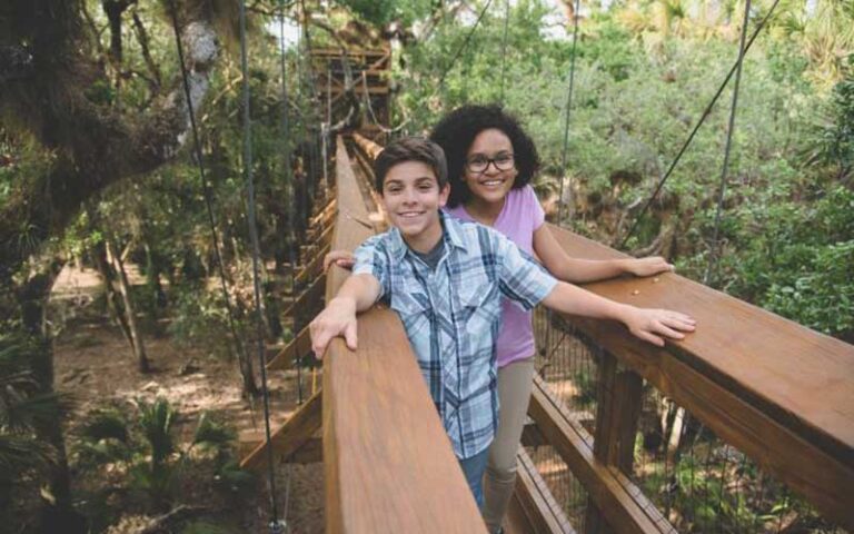 boy and girl on footbridge with tree house in background at myakka river state park sarasota