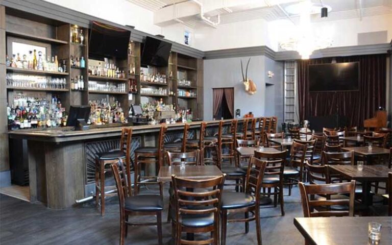 dark wood paneled bar area with tables and chairs at grape grain exchange jacksonville