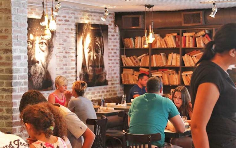 dining room interior with book shelves portraits brick walls and diners at greenstreet cafe miami