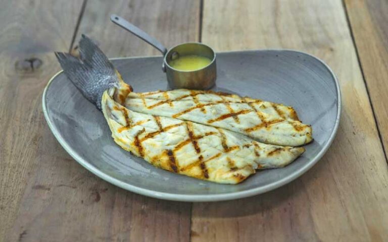 fileted fish grilled with butter sauce plated on wood table at novecento miami