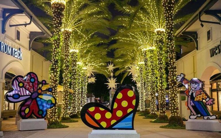 lane between stores in outdoor mall with lit up trees and art sculptures at shops at midtown miami