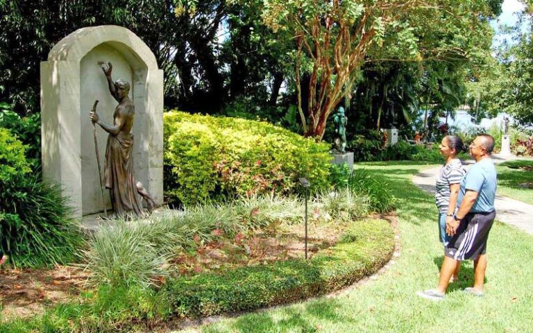 man and woman admire bronze and stone sculpture of man in garden area at albin polasek museum orlando