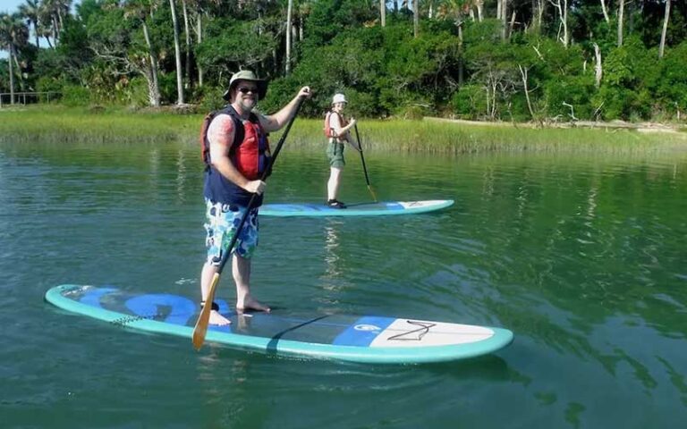 man and woman on separate standup paddle boards on river at kayak amelia jacksonville
