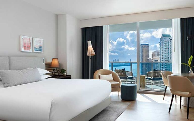 modern hotel room with king bed and balcony with city skyline and bay at kimpton epic hotel miami