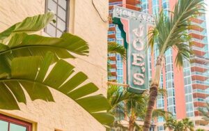 neon sign attached to corner building with trees at joes stone crab miami