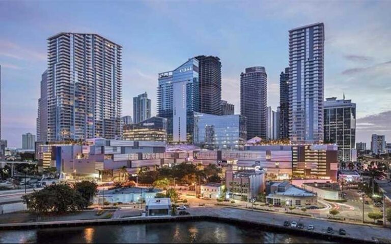 night exterior aerial over bay of lighted buildings at brickell city centre miami